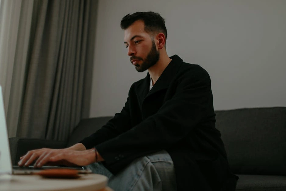 Starší muž studující u notebooku s šálkem kávy.